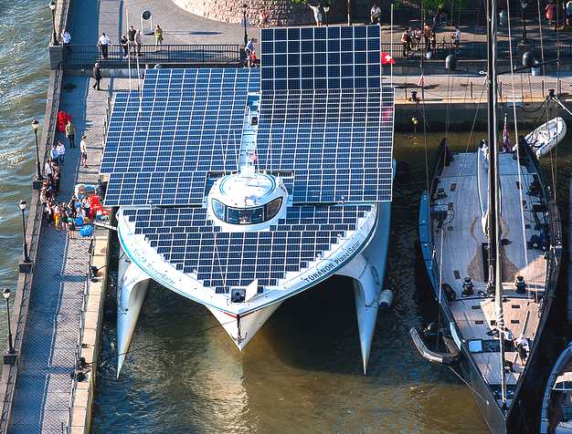 Planetsolar docked alongside a traditional sailing boat