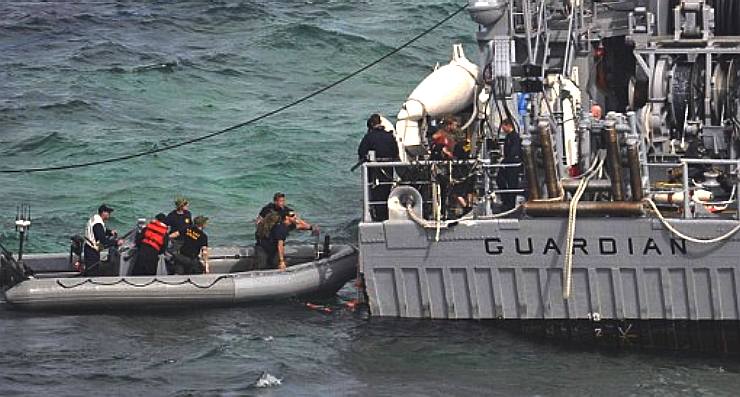 Crew of the USS Guardian frantically unload equipment and potential pollutants